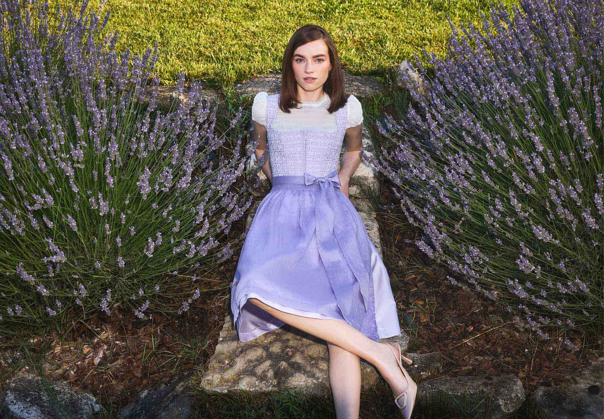De vrouw draagt een bessenkleurige dirndl met een dirndlblouse met driekwart mouwen.