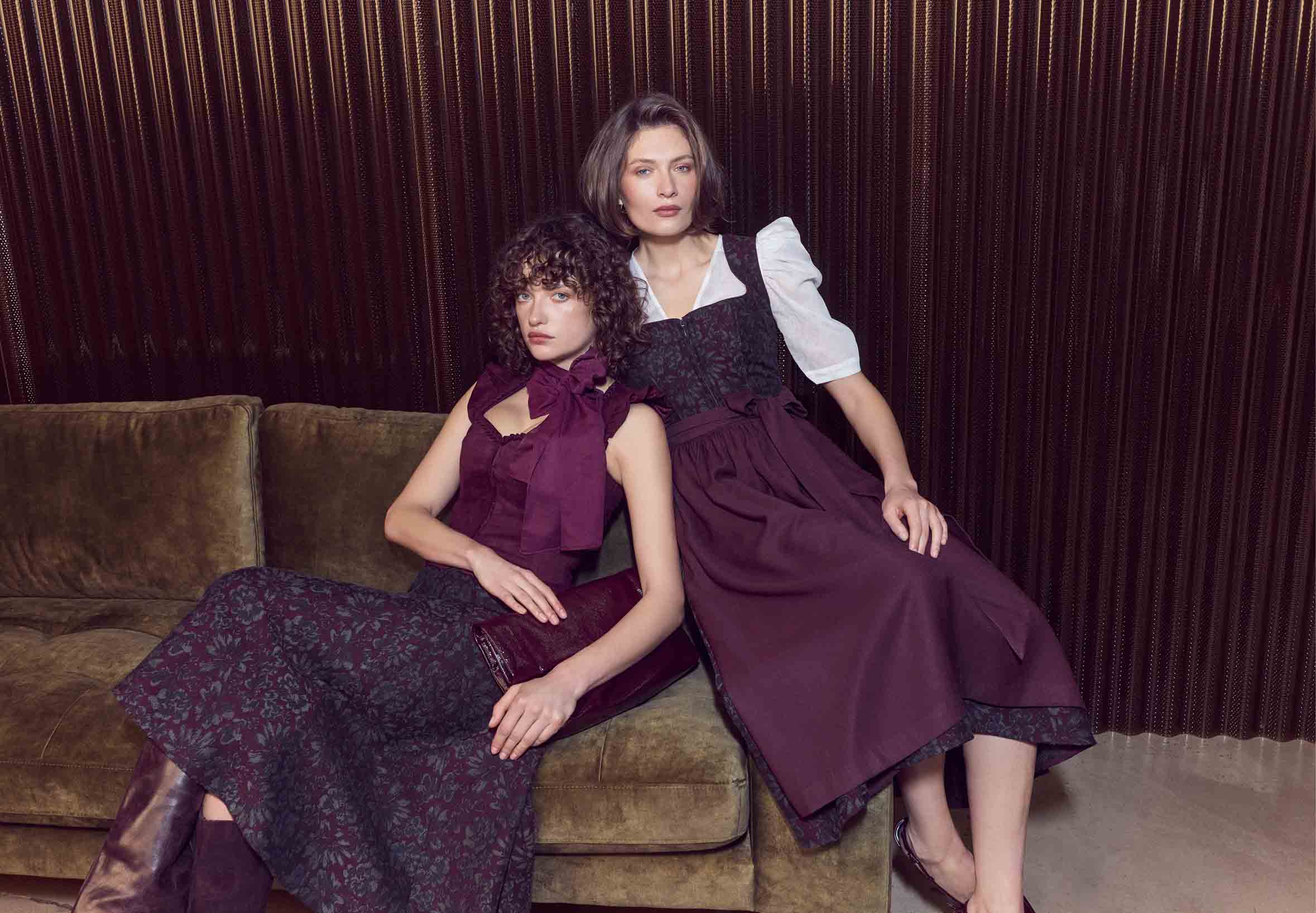 De vrouw draagt een bessenkleurige dirndl met een dirndlblouse met driekwart mouwen.