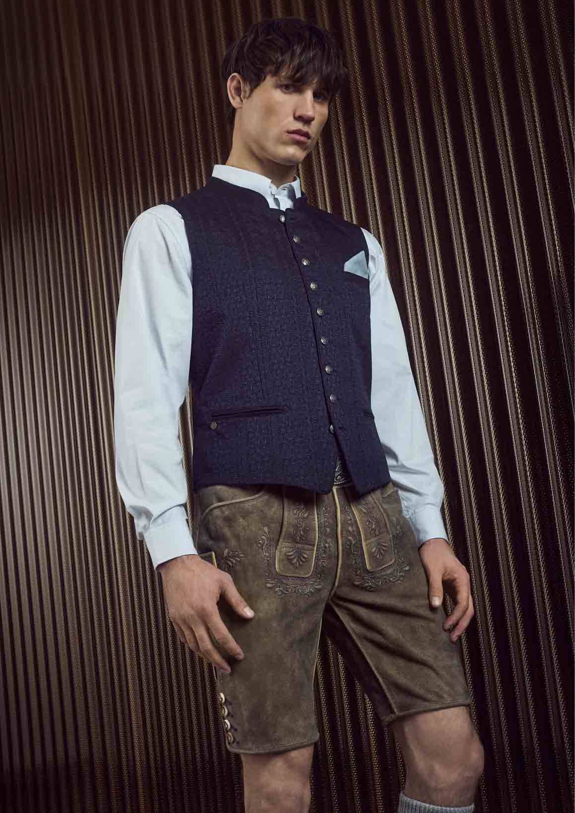 De man draagt een wit overhemd met een zwart vest en een zeer lichte leren broek.